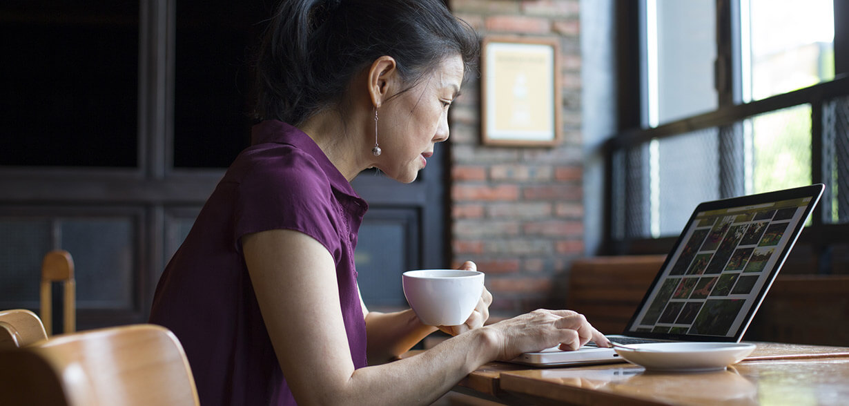 Une femme travaillant sur son ordinateur portable, café à la main